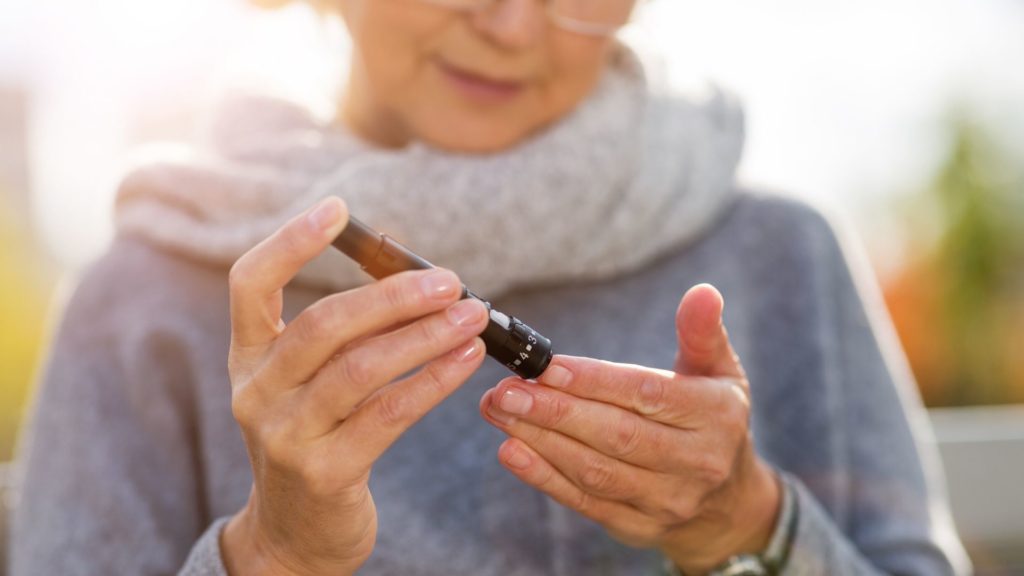 older wman checking blood sugar outside