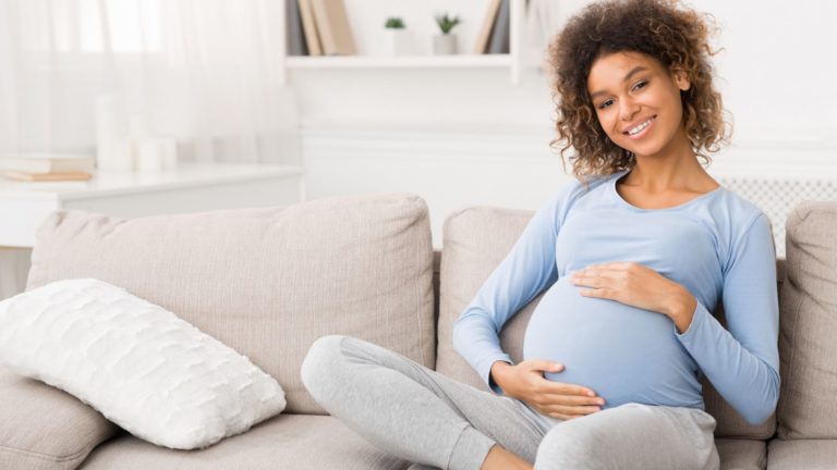pregnant woman wearing blue shirt holding her stomach