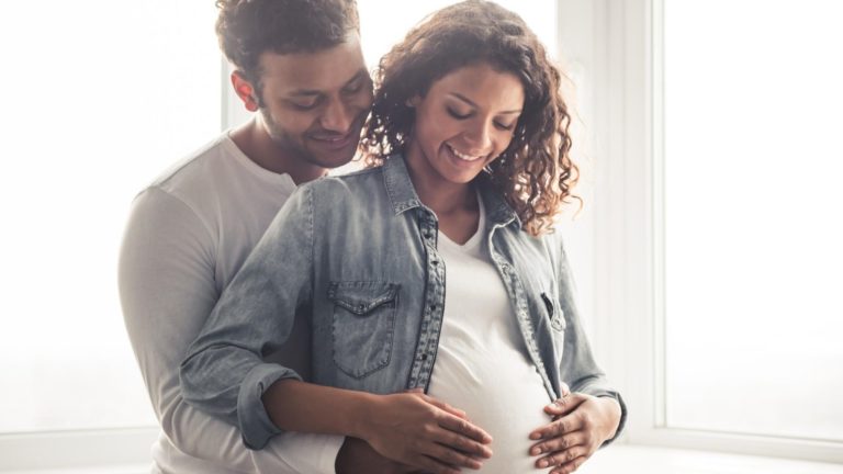 pregnant woman with her husband behind her