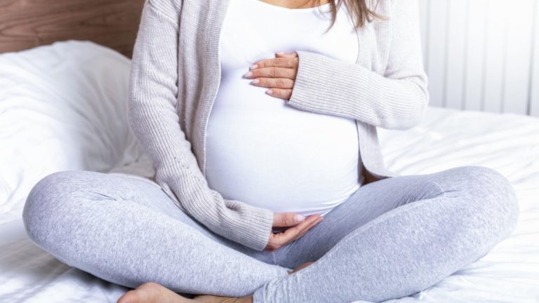 pregnant woman sitting on a bed