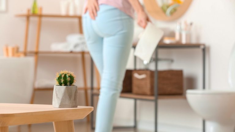 woman standing by toilet with toilet paper