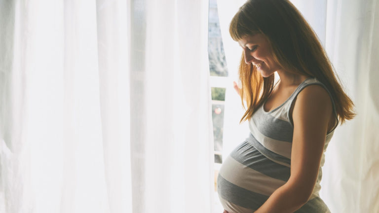 pregnant woman standing in front of window