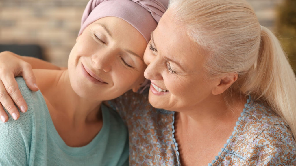 woman with cancer wearing head scarf while being hugged