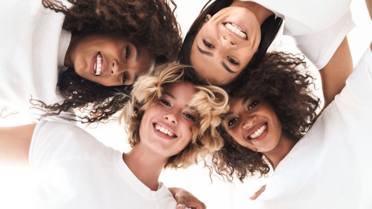 four woman with arms connected standing in a circle