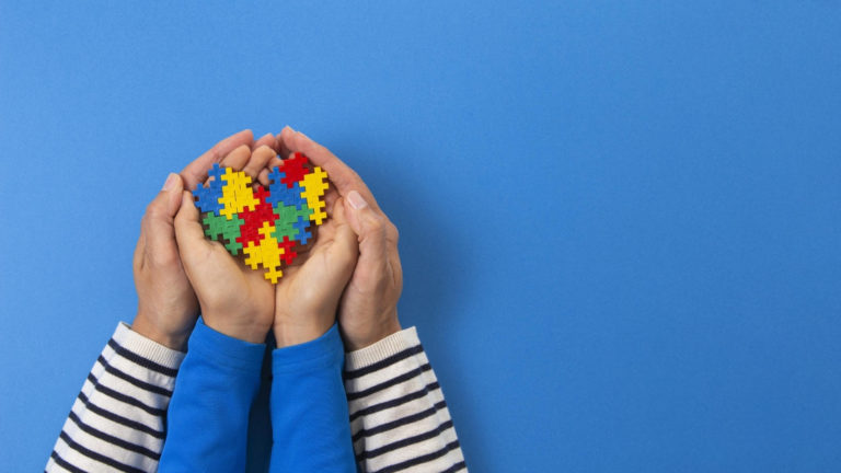 parent and child holding puzzle pieces that form a heart for autism awareness