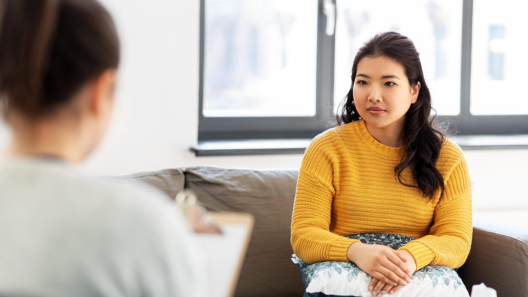oman wearing yellow sweater talking to therapist