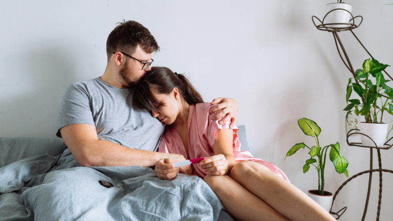 husband consoling wife holding negative pregnancy test