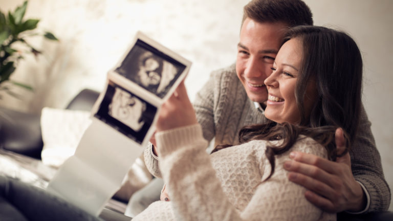 pregnant couple holding an ultrasound photo