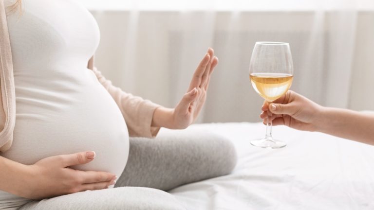 pregnant woman saying no to a glass of wine