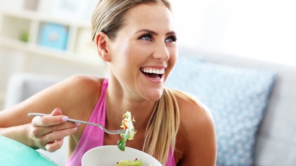 woman smiling eating salad