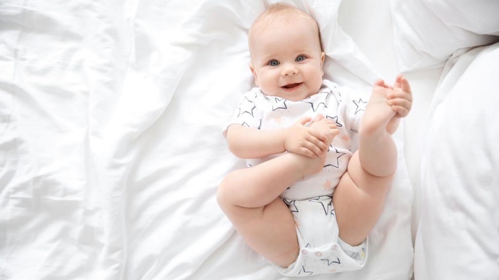 baby smiling holding feet