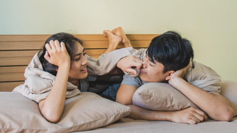 asian couple lying in bed talking