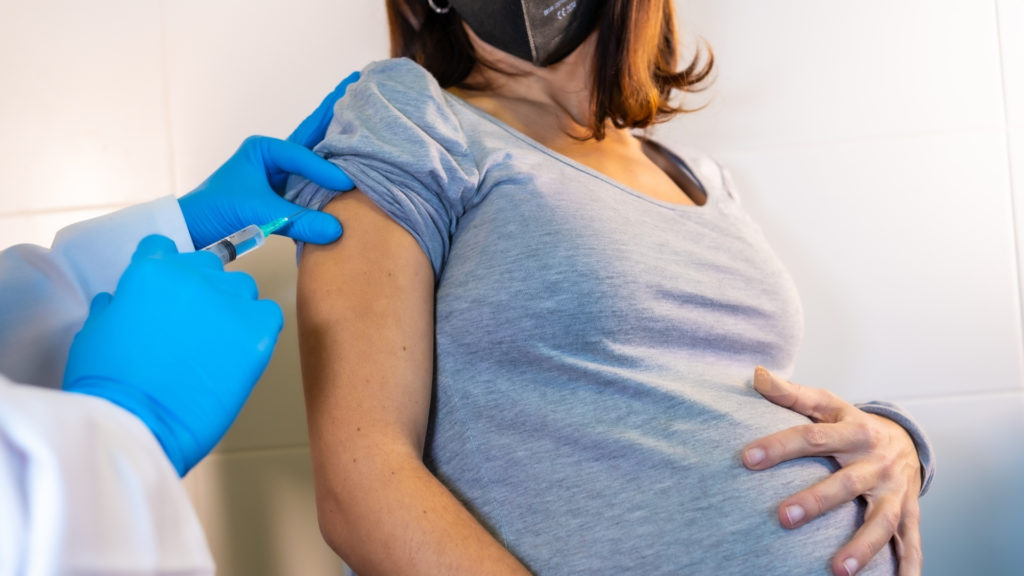 pregnant woman wearing face mask receiving vaccine